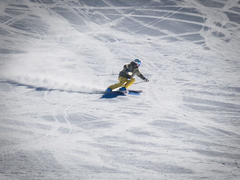 Skier carving turns on a wide, groomed run